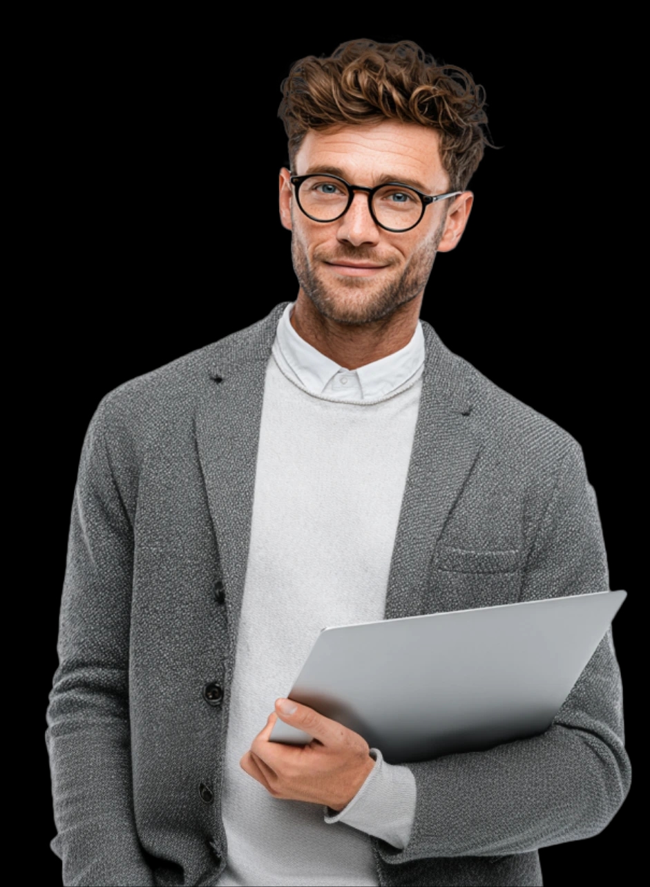Mężczyzna w okularach i szarym swetrze trzymający laptopa, uśmiechający się do aparatu.