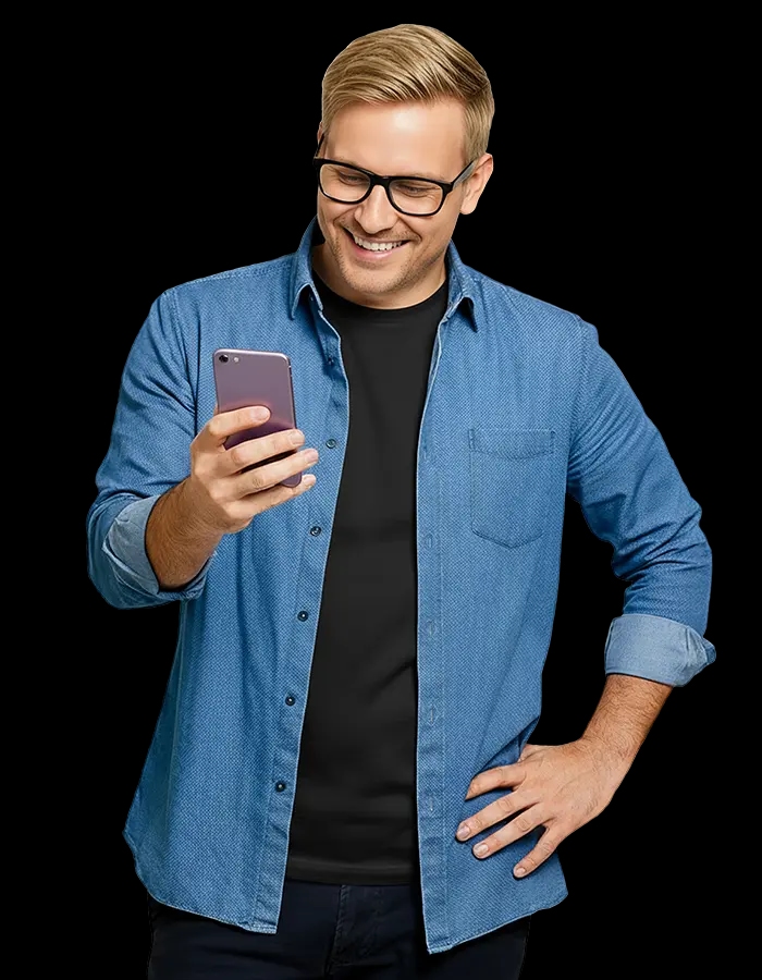 Mężczyzna w okularach i dżinsowej koszuli uśmiecha się, patrząc na smartfon w dłoni.