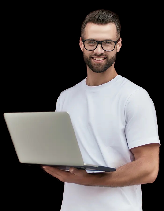 Mężczyzna w okularach trzyma laptop i uśmiecha się do kamery