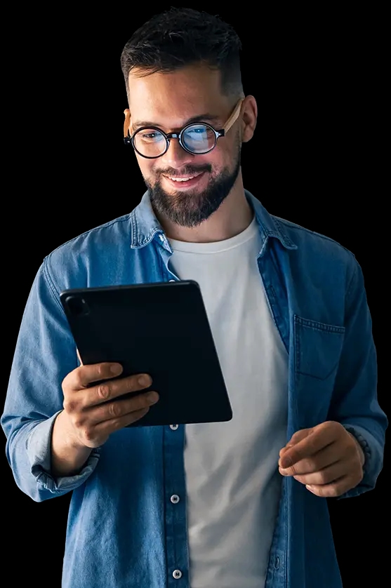 Uśmiechnięty mężczyzna w okularach i dżinsowej koszuli trzyma tablet i patrzy na jego ekran